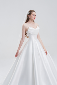 A strapless A-line wedding dress in satin with a sweetheart neckline, pearl and floral embellishments, flowing skirt, and sweeping train for timeless elegance