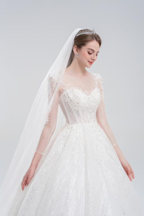 Long sleeve ball gown wedding dress with sparkling tulle, intricate beadwork, and a voluminous skirt for an elegant, romantic bridal look