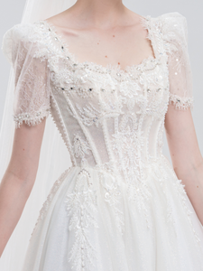 Elegant A-line wedding dress with lace puff sleeves, beaded bodice, and sparkling tulle skirt for a romantic, vintage-inspired bridal look