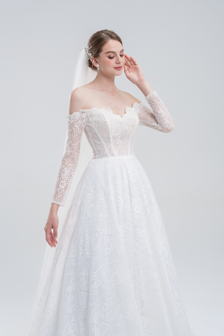 Romantic off-shoulder A-line wedding dress with long lace sleeves, sheer corset bodice, and flowing skirt for a timeless yet modern bridal look