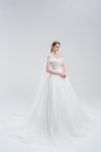 Off-the-shoulder ball gown wedding dress with sparkling tulle, intricate beadwork, and a voluminous skirt for a glamorous fairytale look.
