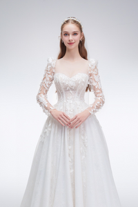 Romantic A-line wedding dress with sheer sleeves, leaf embellishments, sparkling fabric, and beaded details for an ethereal bridal look