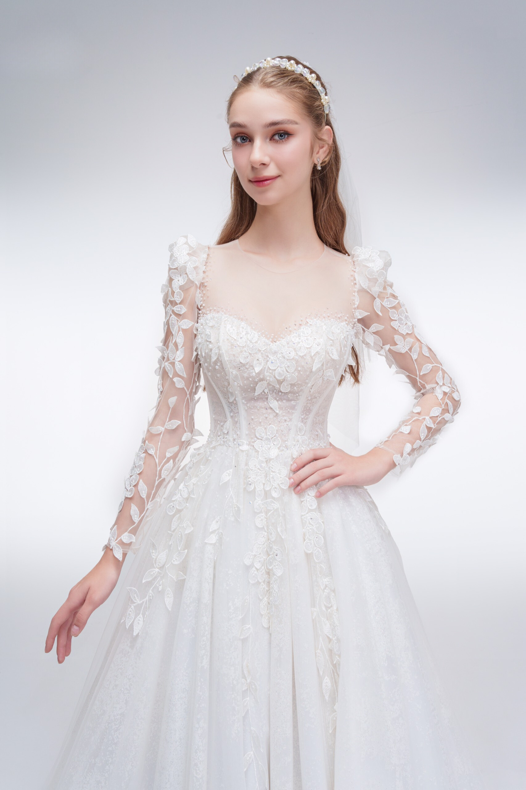 
Romantic A-line wedding dress with sheer sleeves, leaf embellishments, sparkling fabric, and beaded details for an ethereal bridal look