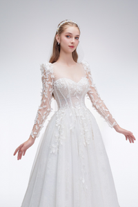 Romantic A-line wedding dress with sheer sleeves, leaf embellishments, sparkling fabric, and beaded details for an ethereal bridal look